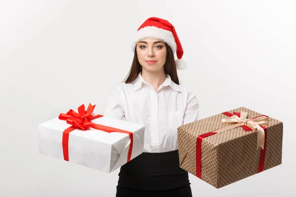 Conceito de Natal - jovem mulher de negócios caucasiana feliz com chapéu de Papai Noel dando uma escolha de caixas de presente para câmera com espaço de cópia no lado . — Fotografia de Stock