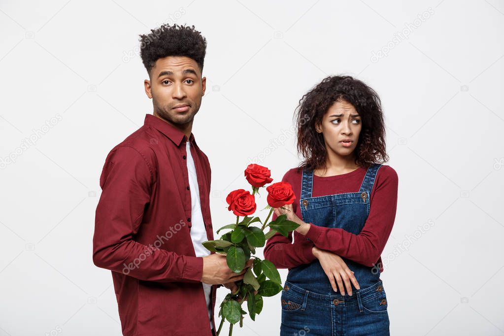 Valentine concept - young african american woman upset and ignore rose from her boyfriend.