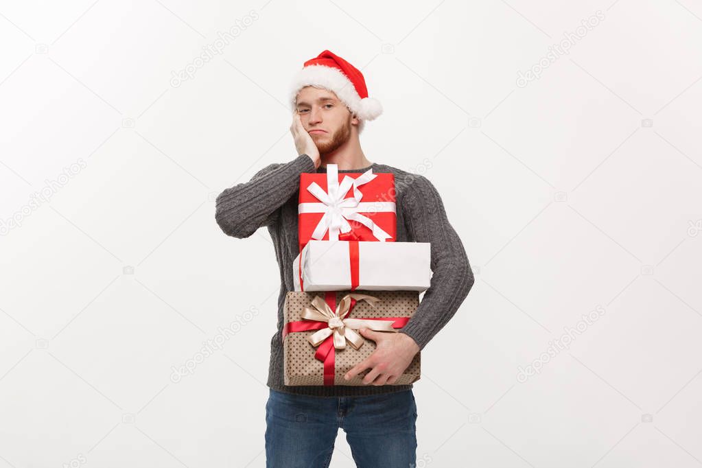 Christmas Concept - young handsome man with beard holding heavy presents with exhausted facial expression on white background.