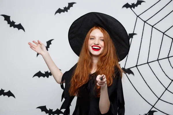 Halloween Concept - mooie heks spelen met magische stok op grijze achtergrond. — Stockfoto