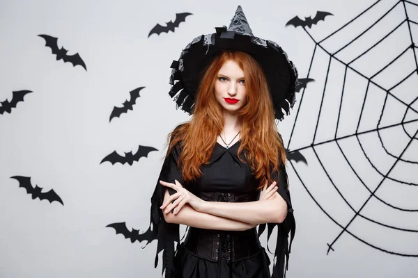 Koncepcja witch halloween - Halloween czarownica trzyma pozowanie z poważną miną nad ciemnym studio szary tło z bat i spider web. — Zdjęcie stockowe