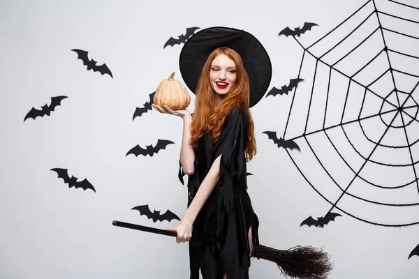 Portrait de belle sorcière caucasienne tenant citrouille pour célébrer Halloween . — Photo