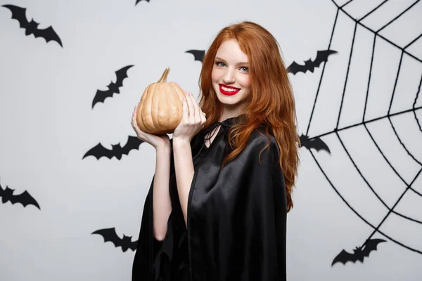 Retrato de una hermosa bruja caucásica sosteniendo calabaza para celebrar Halloween . —  Fotos de Stock