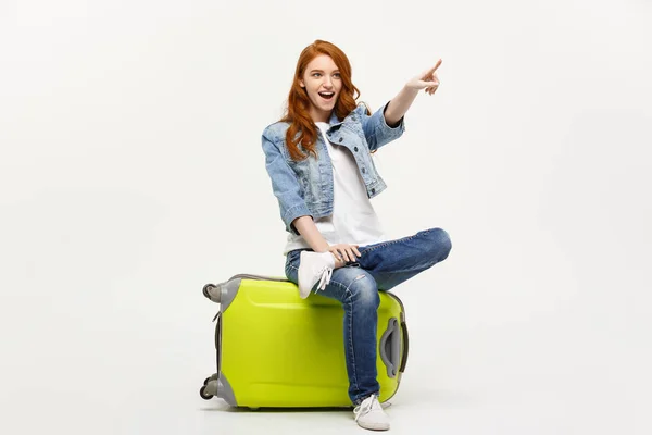 Reise- und Lifestylekonzept: junge kaukasische Frau sitzt auf einem Koffer und weist Richtung. — Stockfoto