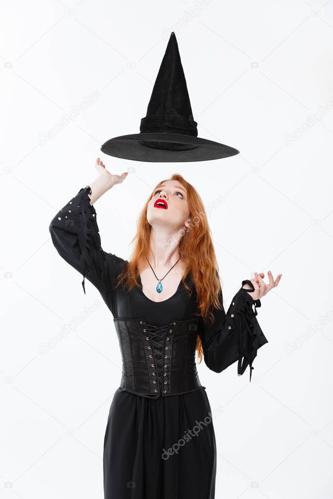 Halloween witch concept - Happy Halloween Sexy ginger hair Witch with magic hat flying over her head. Isolated on white background.
