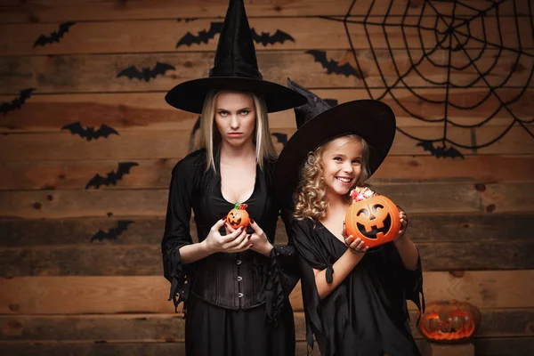 Halloween koncepció - gyönyörű kaukázusi anya, boldog kis daugther csalódott érzéssel élvezze Halloween cukorkát, édes denevérek és pókháló fa stúdió-háttér. — Stock Fotó