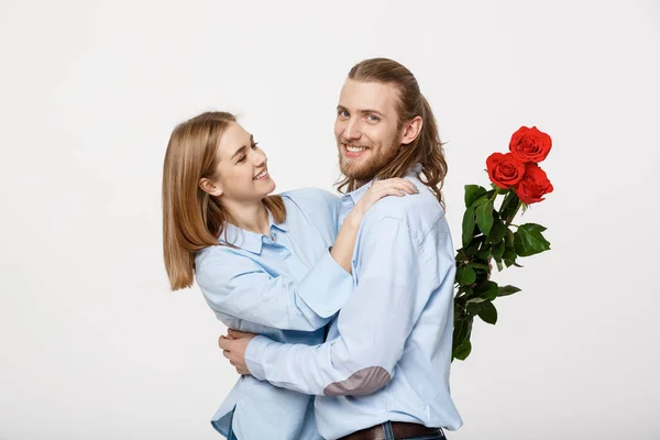 Retrato de un joven atractivo escondiendo flores de su novia antes de darle una sorpresa sobre fondo blanco aislado . —  Fotos de Stock