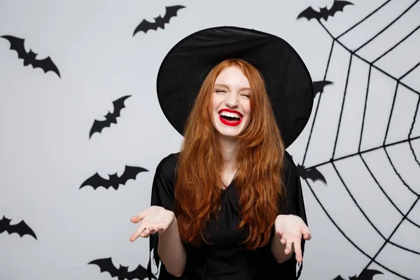 Halloween koncepció - gyönyörű boszorkány kezemet, és mosolyogva, mint szürke háttér. — Stock Fotó