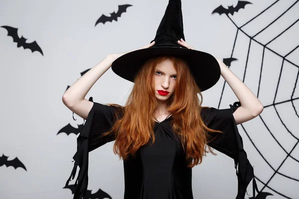 Halloween koncepció - gyönyörű súlyos boszorkány dühös arc kifejezése, mint szürke háttér. — Stock Fotó