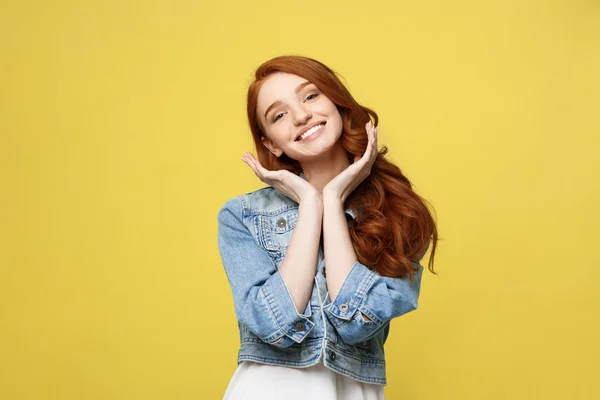 Concepto de estilo de vida: Hermosa joven sonriente en ropa de jean posando con las manos en la barbilla. Aislado sobre fondo amarillo . — Foto de Stock