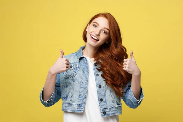 Lifestyle Concept: Satisfied successful girl with thumb up gesture on golden yellow background
