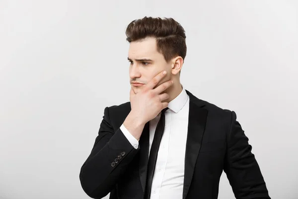 Geschäftskonzept: junger, gutaussehender Geschäftsmann im Anzug, der mit der Hand am Kinn denkt, Geschäftsstrategien-Konzept — Stockfoto
