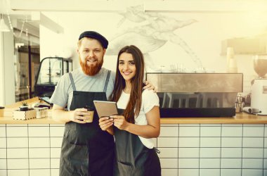 Kahve iş kavramı - online sipariş için onların tablet bakarak neşeli baristas.