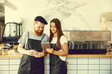 Kahve iş kavramı - online sipariş için onların tablet bakarak neşeli baristas.