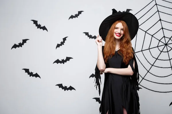 Halloween boszorkány koncepció - Happy Halloween boszorkány holding, pózol, mint sötét szürke stúdió háttere, a denevér és a spider web. — Stock Fotó