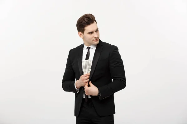 Business Concept: Bello uomo d'affari in abito nero che prende banconote in dollari con espressione furtiva su sfondo bianco . — Foto Stock