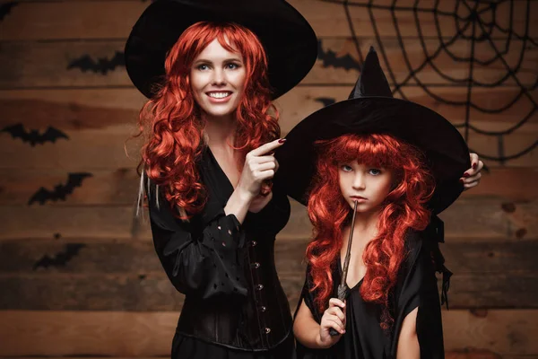 Koncept Halloween - krásná kavkazské matka zdobit její dceři v čarodějnických kostýmů a dlouhé kudrnaté vlasy připravené pro oslavu Halloween. — Stock fotografie