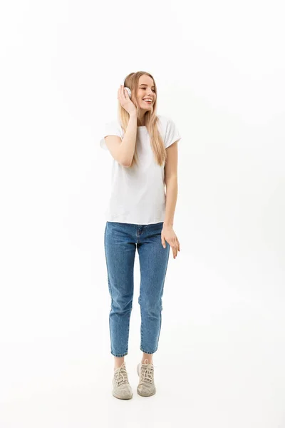 Concepto de estilo de vida: Retrato de una alegre estudiante feliz escuchando música con auriculares mientras baila aislada sobre fondo blanco — Foto de Stock