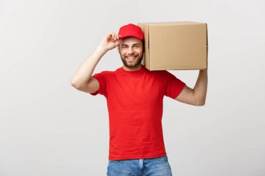 Teslimat Konsepti: genç beyaz yakışıklı teslimatçı omuzunda bir kutu tutuyor. Gri arkaplan üzerinde izole.