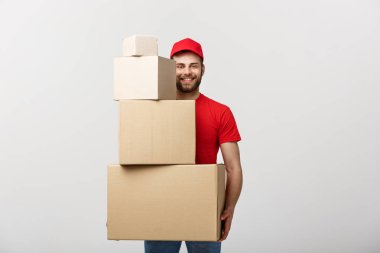 Teslimat kavramı: Yakışıklı teslimat adam tutun kazık karton kutular gri arka plan üzerinde.