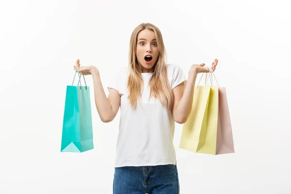 Lifestylekonzept: Porträt schockiert junge brünette Frau in weißem Sommerhemd posiert mit Einkaufstaschen isoliert über weißem Hintergrund. — Stockfoto