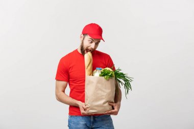 Teslimat Konsepti - Yakışıklı Kakasyalı teslimatçı marketten bir paket yiyecek ve içecek getirdi. Grey Stüdyo Arkaplanı 'nda izole edilmiş. Boşluğu Kopyala.