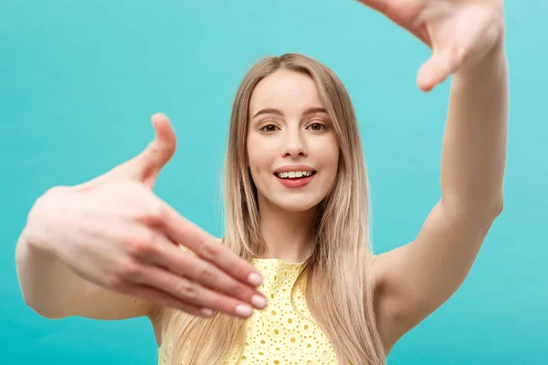 Close-up Mujer joven caucásica cuidado de la cara y los ojos y ella haciendo marco con las manos aisladas sobre fondo azul pastel . — Foto de Stock