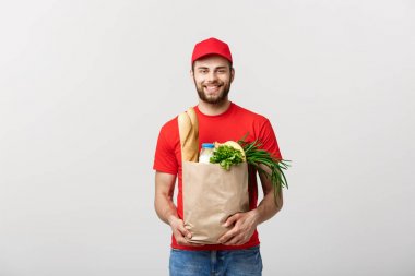 Teslimat Konsepti - Yakışıklı Kakasyalı teslimatçı marketten bir paket yiyecek ve içecek getirdi. Grey Stüdyo Arkaplanı 'nda izole edilmiş. Boşluğu Kopyala.