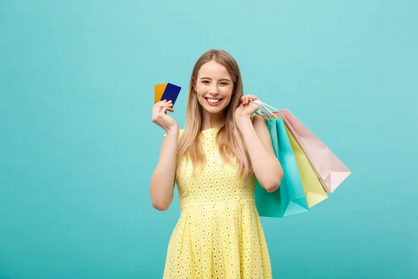 Compras y Lifestyle Concept: Hermosa joven con tarjeta de crédito y bolsas de compras de colores. Aislado sobre fondo azul — Foto de Stock