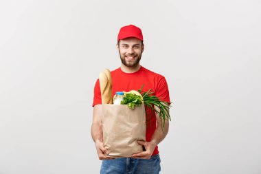 Teslimat Konsepti - Yakışıklı Kakasyalı teslimatçı marketten bir paket yiyecek ve içecek getirdi. Grey Stüdyo Arkaplanı 'nda izole edilmiş. Boşluğu Kopyala.