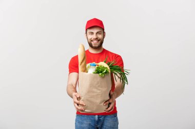 Teslimat Konsepti - Yakışıklı Kakasyalı teslimatçı marketten bir paket yiyecek ve içecek getirdi. Grey Stüdyo Arkaplanı 'nda izole edilmiş. Boşluğu Kopyala.