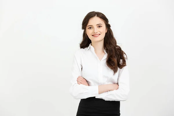 Концепція бізнесу: Портрет впевненої молодої бізнес-леді, яка тримає руки перехрещеними і дивиться на камеру, стоячи на сірому фоні — стокове фото