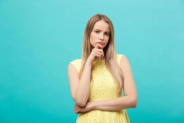 Denken vertrouwen jongedame in gele jurk opzoeken van geïsoleerde op blauwe achtergrond — Stockfoto