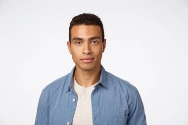 Yakın plan yakışıklı, şık İspanyol tişörtlü, rahat, sakin yüzlü kameraya bak, neşeli gülümse, beyaz arka plan, ürünü tanıt, reklam panosu reklamını yap.