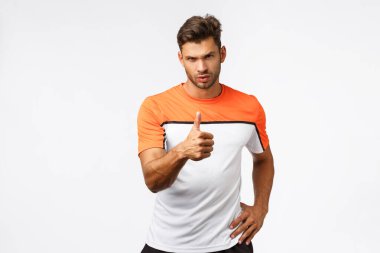 Spor, antrenman ve spor konsepti. Şımarık, yakışıklı, erkeksi sakallı genç adam, sporcu, başparmak kaldıran ve kameraya bakan memnun, müşterinin harika iş çıkarmasından memnun, harika iş çıkarmandan övgüyle bahseden adam.