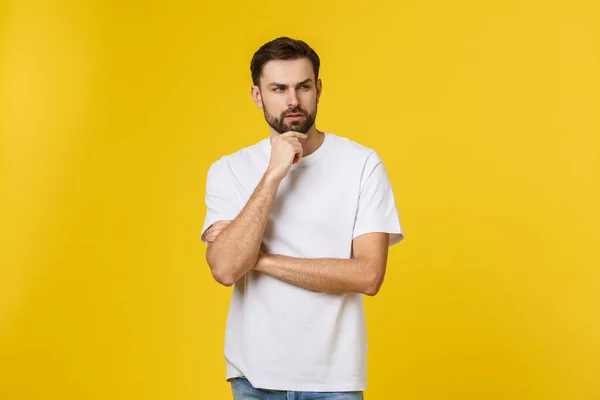 Hombre curioso pensativo mirando hacia arriba en la pose de pensamiento tratando de hacer elección o decisión aislado en el fondo amarillo . — Foto de Stock