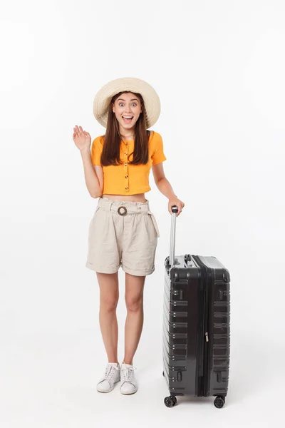 Γυναίκα τουρίστρια. Full length ευτυχισμένη νεαρή γυναίκα στέκεται με τη βαλίτσα με συναρπαστικό gesturing, απομονώνονται σε λευκό φόντο. — Φωτογραφία Αρχείου