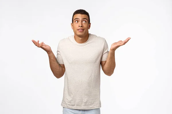 Indecisive and unaware handsome young hispanic man, shrugging clueless, look away, cant answer, dont know anything, standing white background without any clue how solve situation, being uncertain — Stock Photo, Image