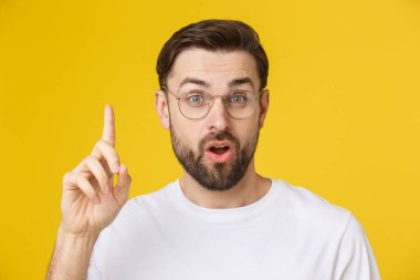 Kopyalama alanına bakan genç adam sarı arka planda şaşırmış ya da tatmin olmuş bir görünüm sergiliyor..