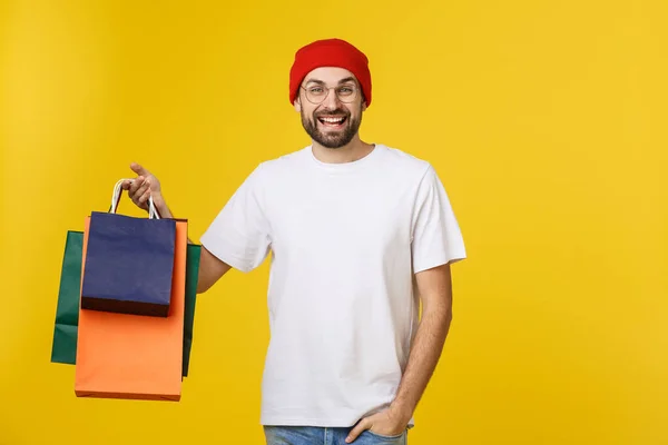 Uomo barbuto con borse della spesa con sensazione felice isolato su bacino giallo — Foto Stock