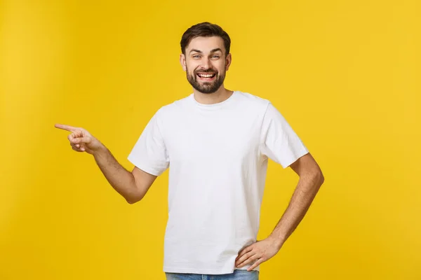 Man pointing showing copy space isolated on yellow background. Casual handsome Caucasian young man. — Stock Photo, Image