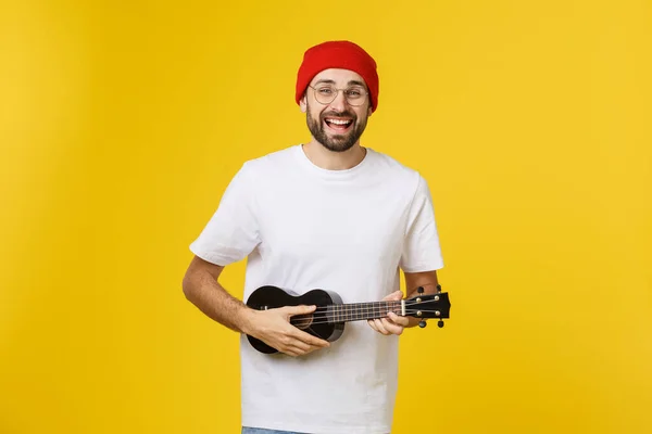 Ung, kjekk gitarist. Studio filmet på gul bakgrunn . – stockfoto