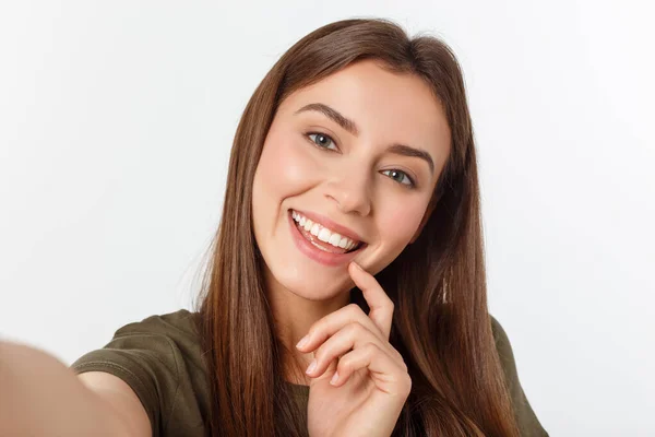 Retrato de una linda mujer sonriente haciendo foto selfie en un teléfono inteligente aislado sobre un fondo blanco . —  Fotos de Stock