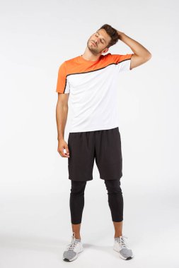 Tam boy dikey atış musuline çekici genç sporcu aktif giyimli, başını eğ, saçlarını koluna daya, gerilimi azaltmak için boynunu uzat, futbol maçından önce egzersiz yap, vücudunu antrenmana hazırla.