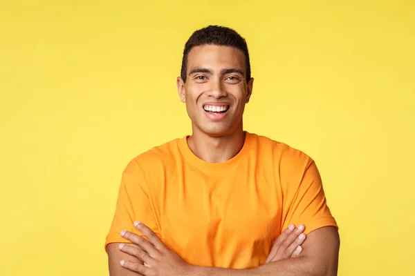 Joyful smiling handsome masculine man in t-shirt, cross arms chest confident, laughing as having carefree, relaxing conversation during party, standing yellow background upbeat, self-assured — Stock Photo, Image