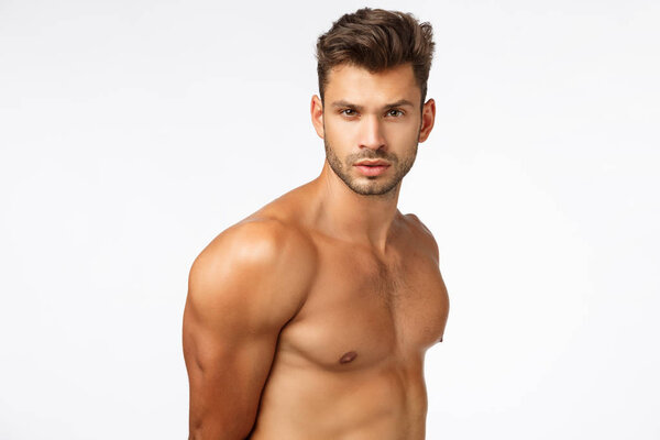 Gym, sport and bodybuilding concept. Waist-up masculine sexy young man with naked torso, six packs perfect body, turn face camera and look self-assured, determined, getting strong in fitness club