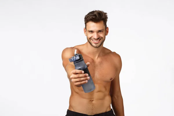 Sexy handsome and self-assured sportsman give you water bottle drink and refresh, smiling confident, posing naked torso. Shirtless sassy athlete give drink after productive fitness workout — Stock Photo, Image