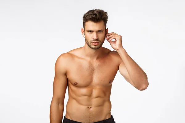 Prontos, firmes, vão. Sexy, bonito sem camisa jovem barbudo homem com perfeito tronco nu, seis pack, corpo muscular atraente, usar fones de ouvido sem fio, olhar determinado, começar a treinar e ouvir música — Fotografia de Stock