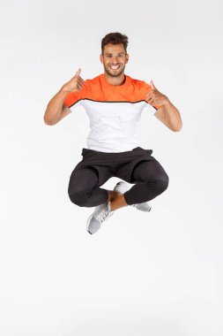 Tam boy şut atlama, hareketli çekim mutlu gülümseyen sporcu onaylı başparmak gösterme ya da egzersiz için harika bir yer tavsiye, spor promosyonu, iyi fitness ekipmanları ile tatmin