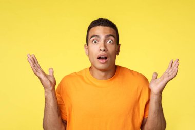 Etkilenmiş ve hayal kırıklığına uğramış genç adam oyunda bahsi kaybetti, ellerini yana açtı umutsuzca ya da kararsız bir jest, ağzı açık, şok olmuş bakışlı kamera nutku tutuldu, sarı arka planda dikildi.